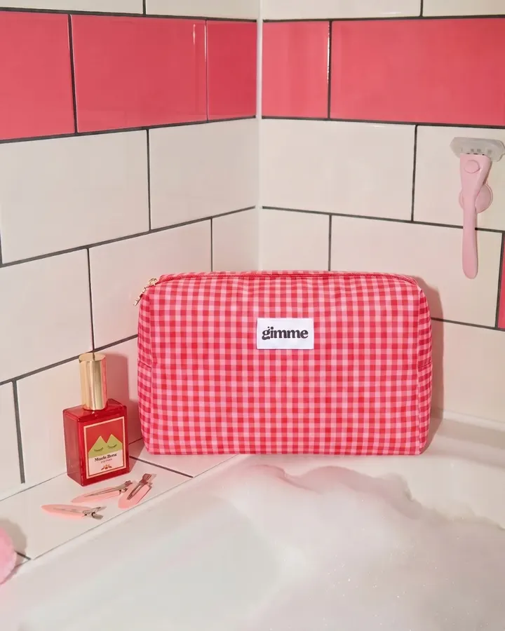 Red and pink gingham makeup pouch on a bathtub edge
